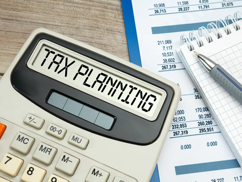 Calculator display reading Tax Planning beside a calendar and pen